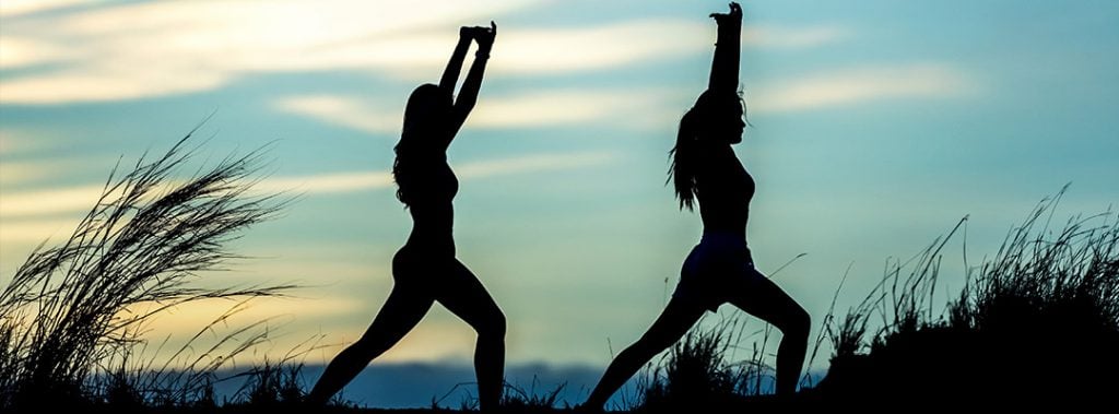 silhouette of two women in yoga poses